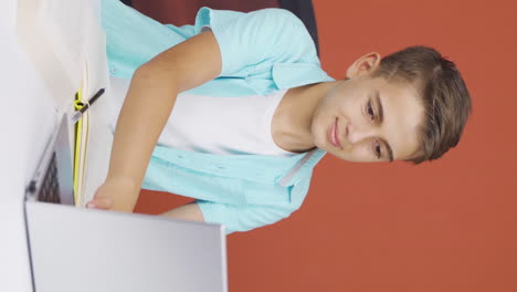 Vertical-video-of-Boy-working-on-laptop-with-happy-expression.